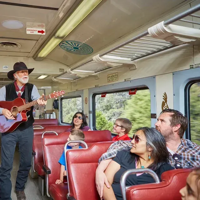 A man singing and playing a guitar on a train