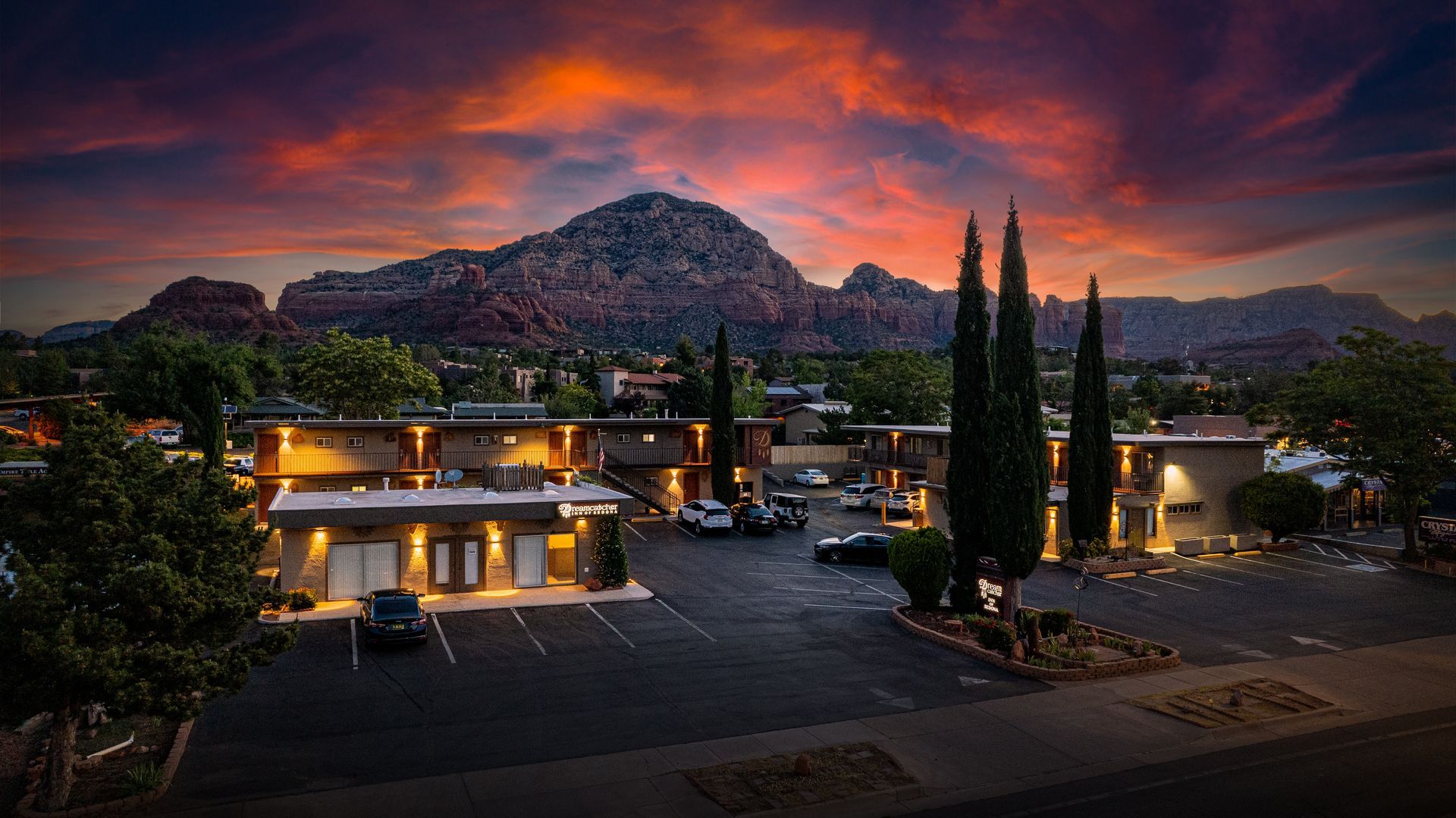 An aerial view of a hotel with a mountain in the background at sunset.
