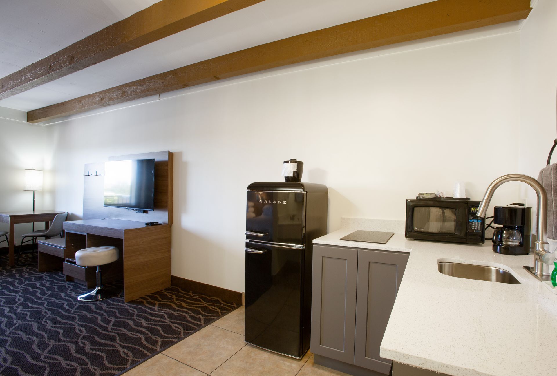 A hotel room with a kitchen and a refrigerator.