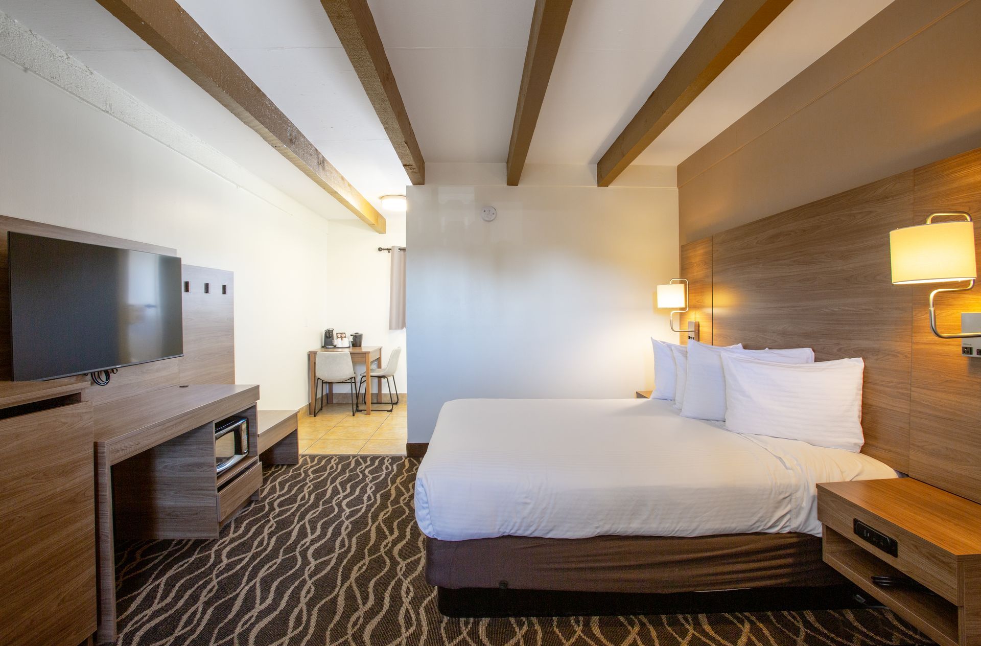 A hotel room with a king size bed and a flat screen tv.