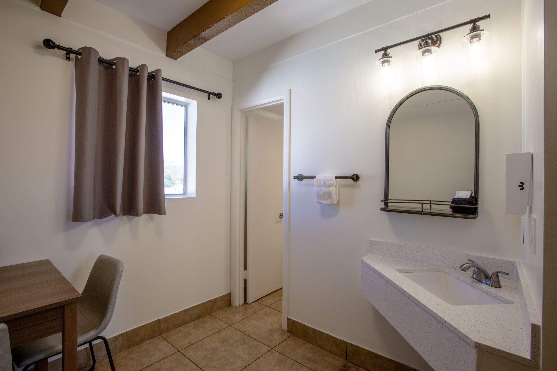 A bathroom with a sink , mirror and table.