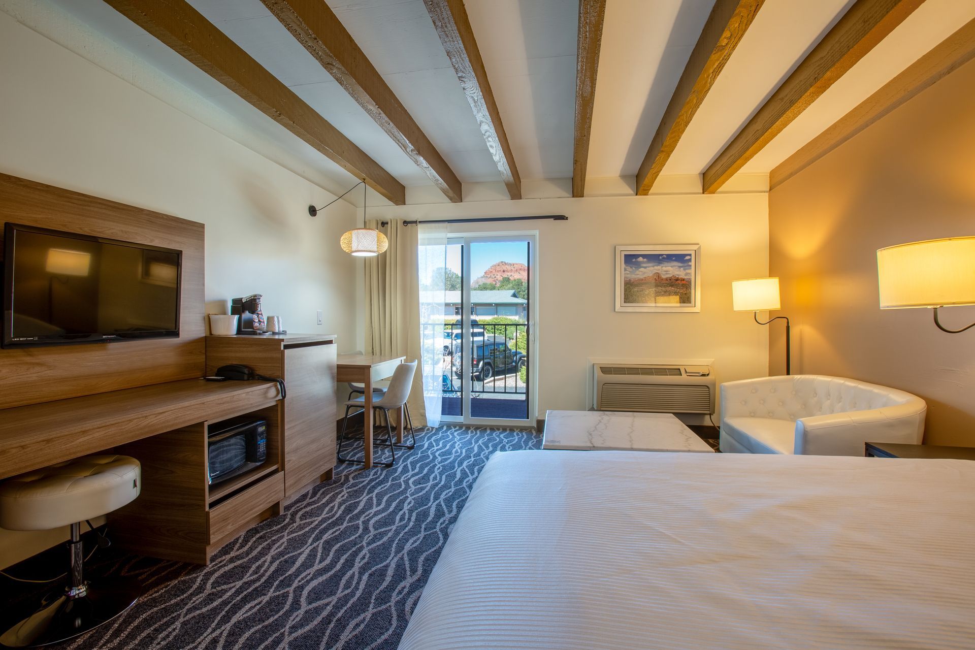 A hotel room with a king size bed , chair , desk and television.