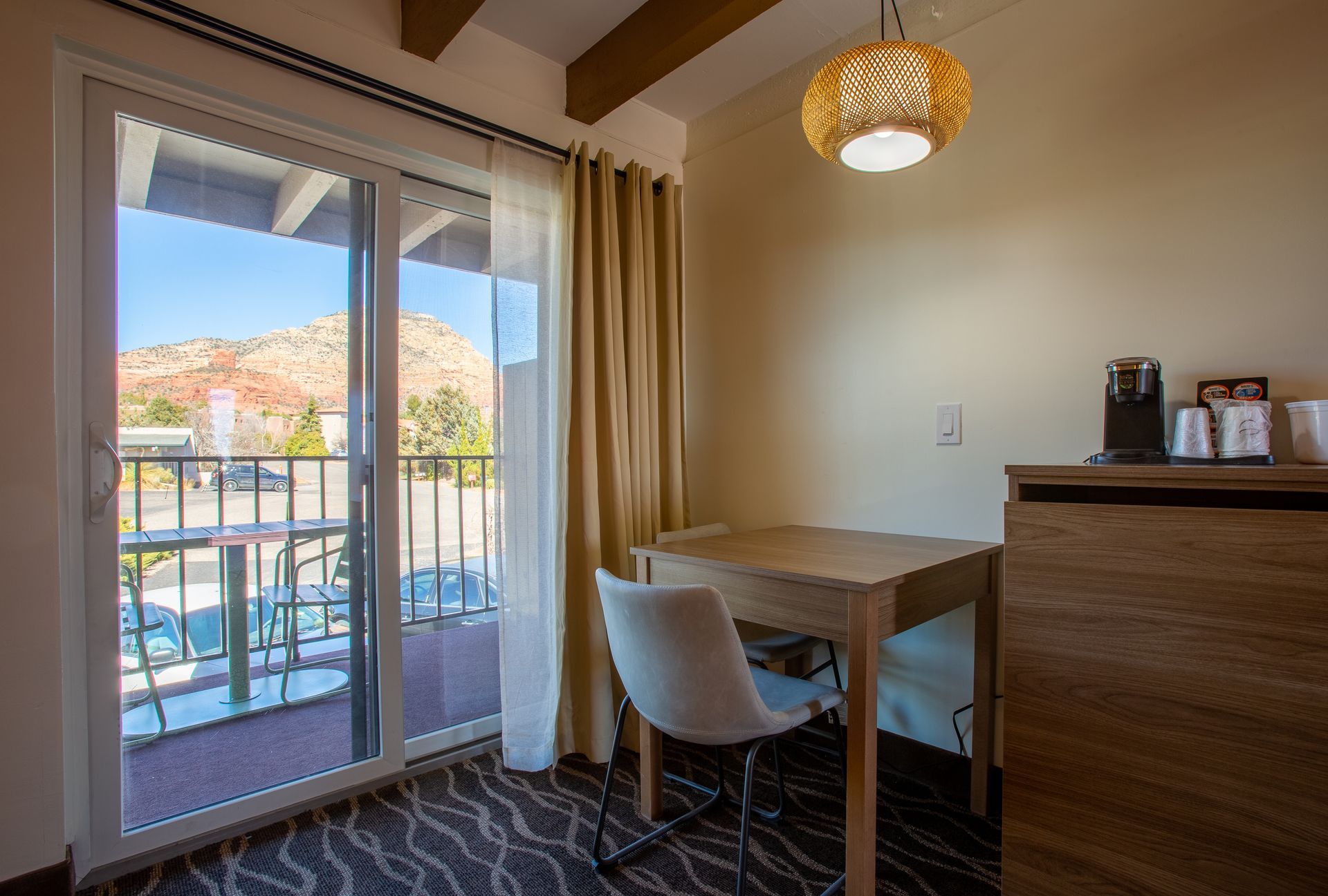 A hotel room with a table and chairs and a sliding glass door leading to a balcony.