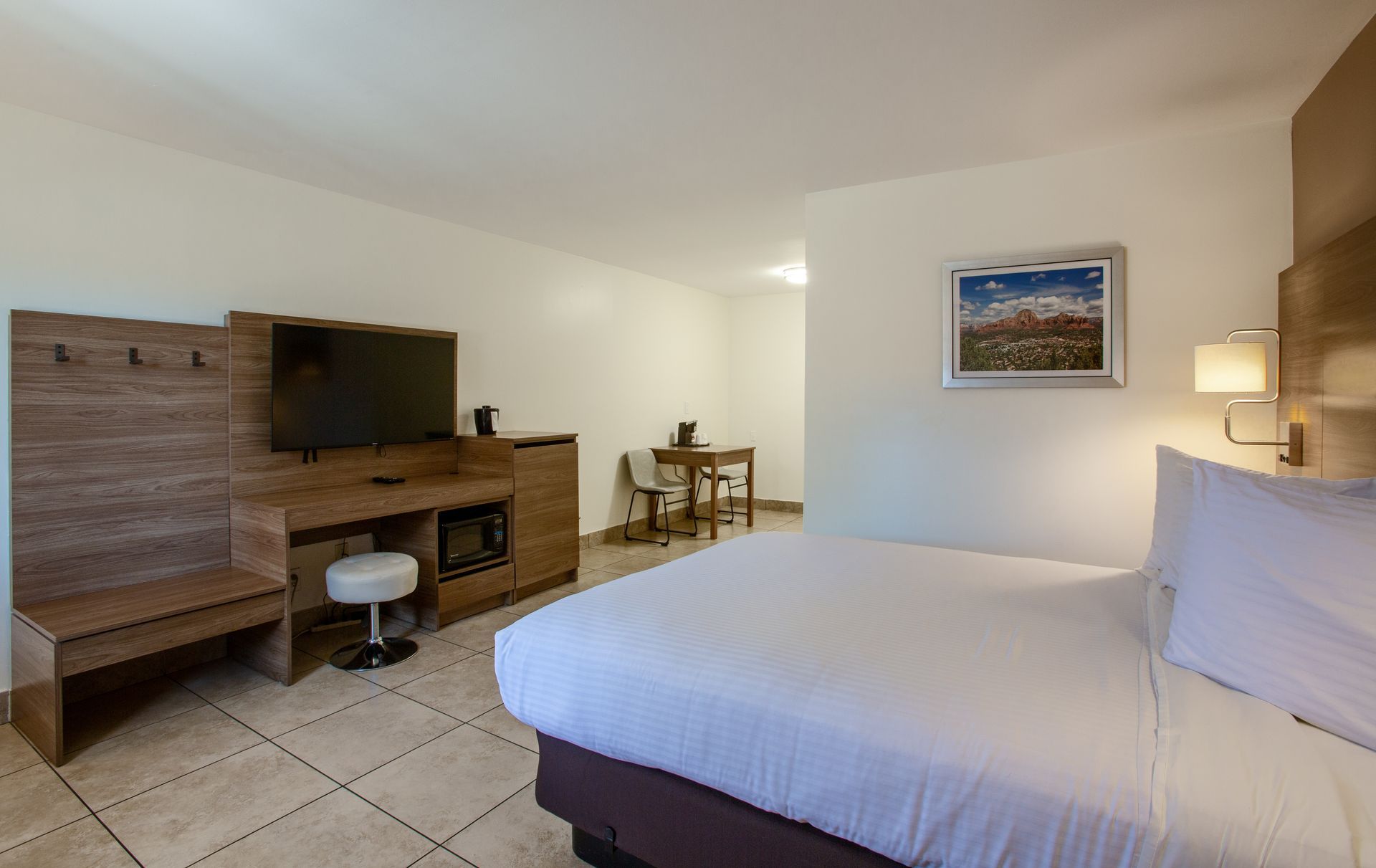 A hotel room with a king size bed , television , desk and chairs.