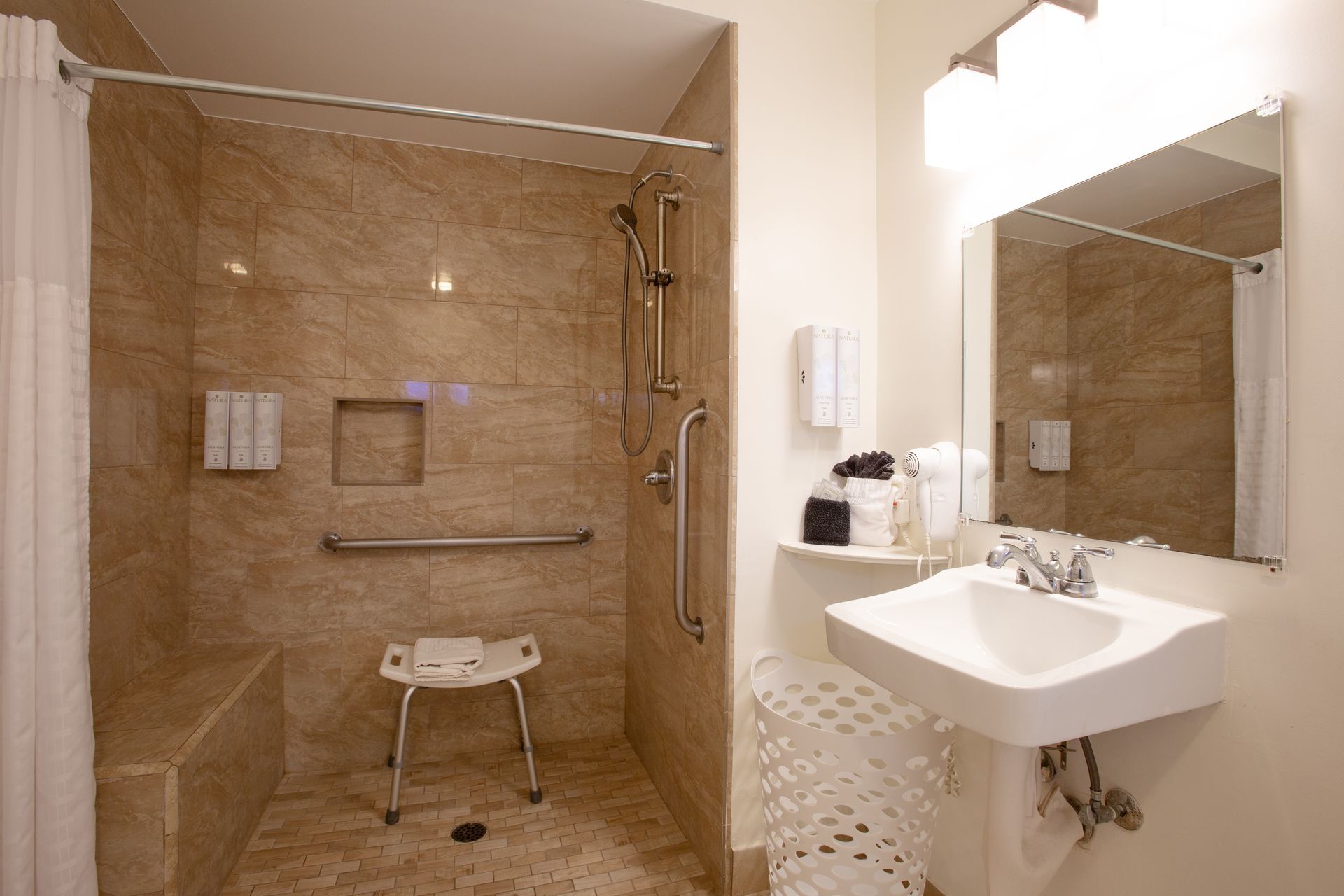 A bathroom with a walk in shower , sink and mirror