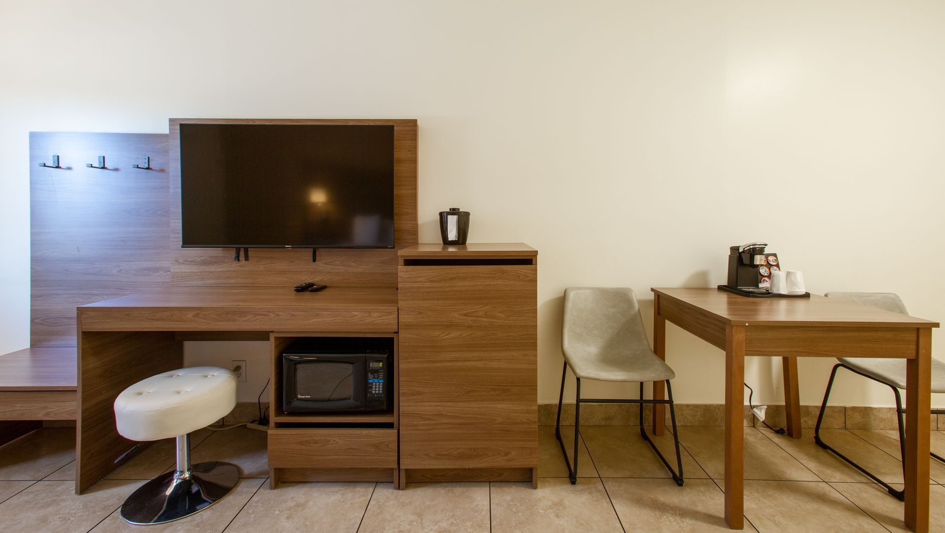 A hotel room with a desk , chairs , microwave and television.