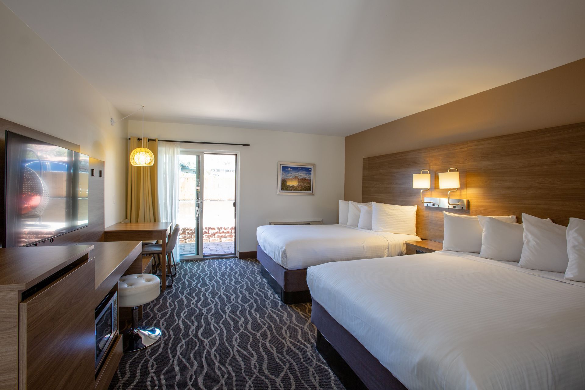 A hotel room with two beds , a desk and a television.