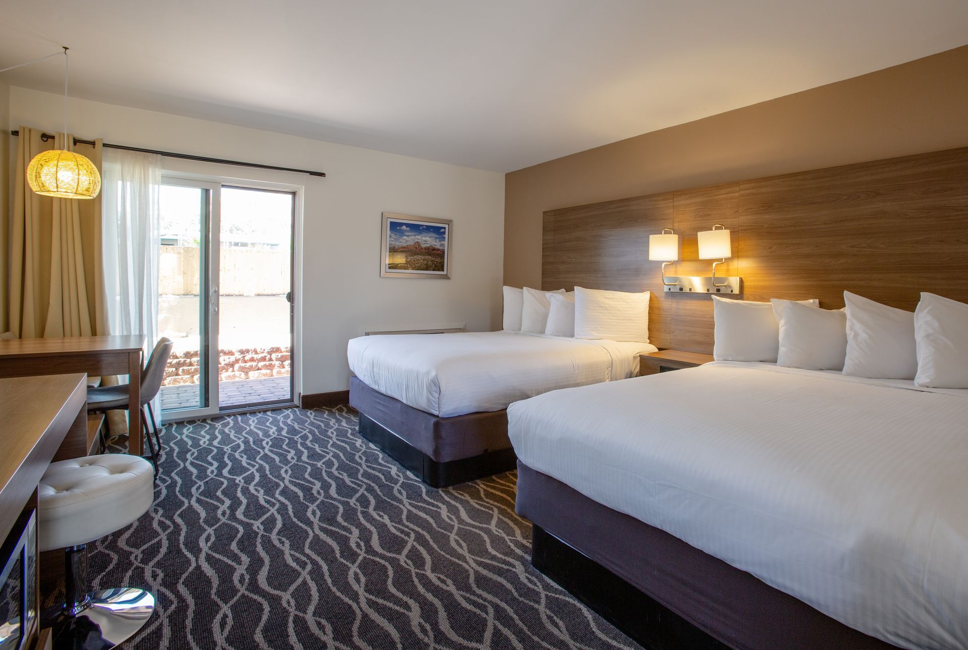 A hotel room with two beds and a sliding glass door.