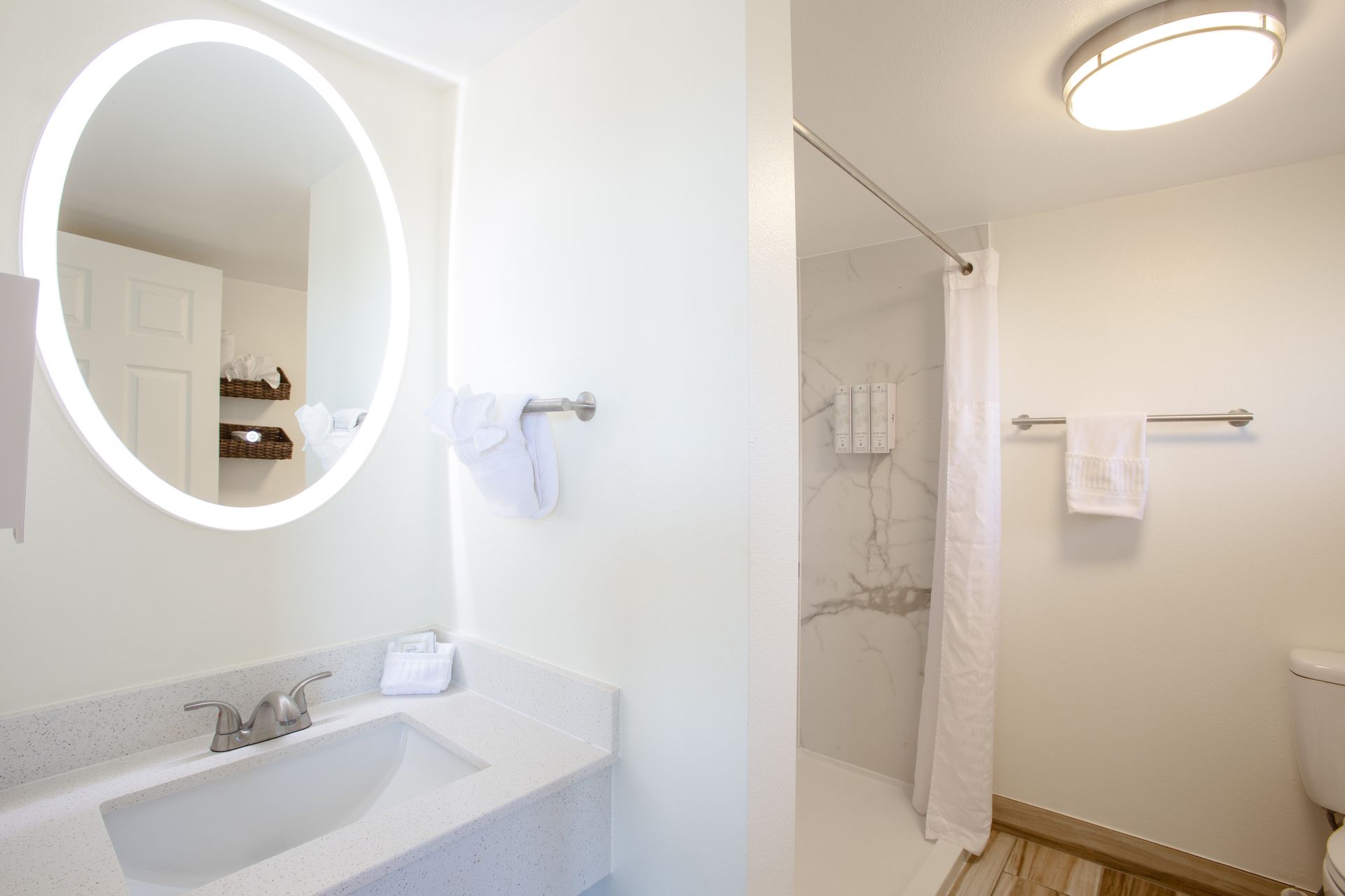 A bathroom with a sink , toilet , shower and mirror.