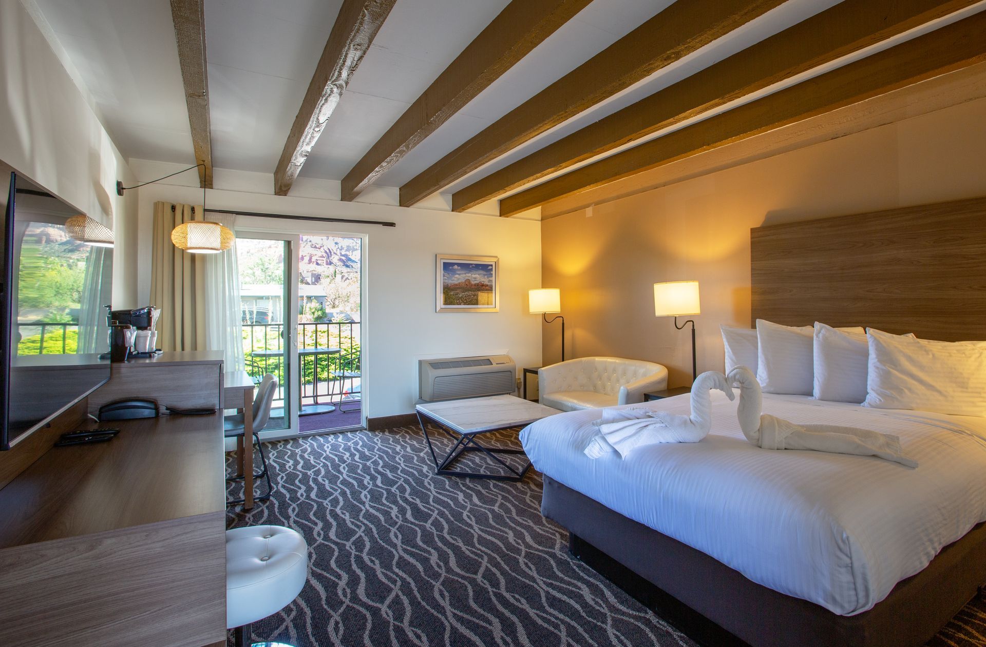 A hotel room with a king size bed , desk , chair and television.