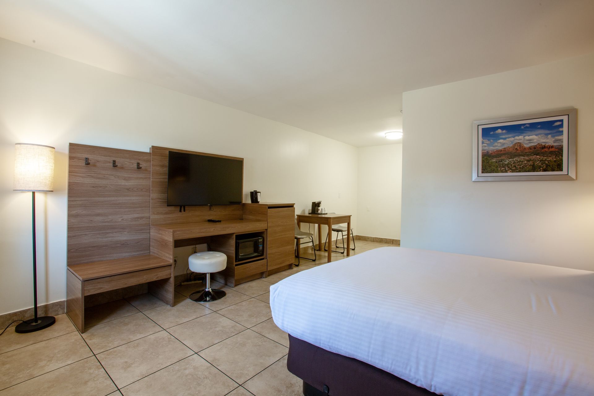 A hotel room with a bed , television , desk and chair.