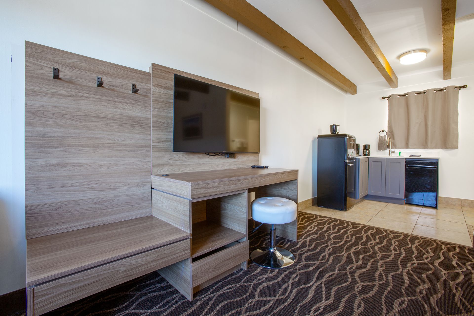 A hotel room with a flat screen tv and a stool.