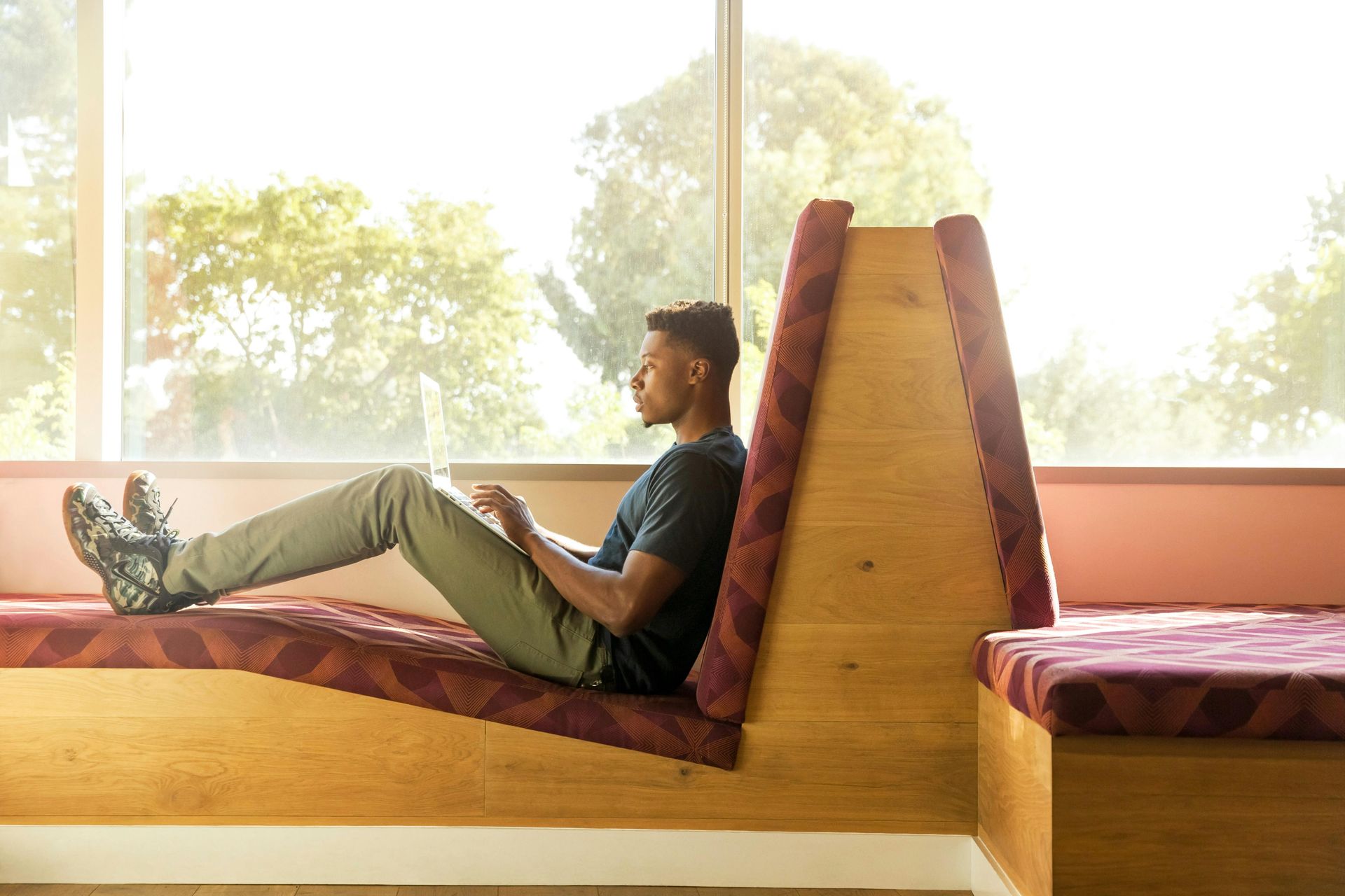 A man is sitting on a couch using a laptop computer.