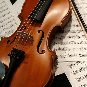 Close-up of a violin on sheet music, with warm wood tones and a bow nearby
