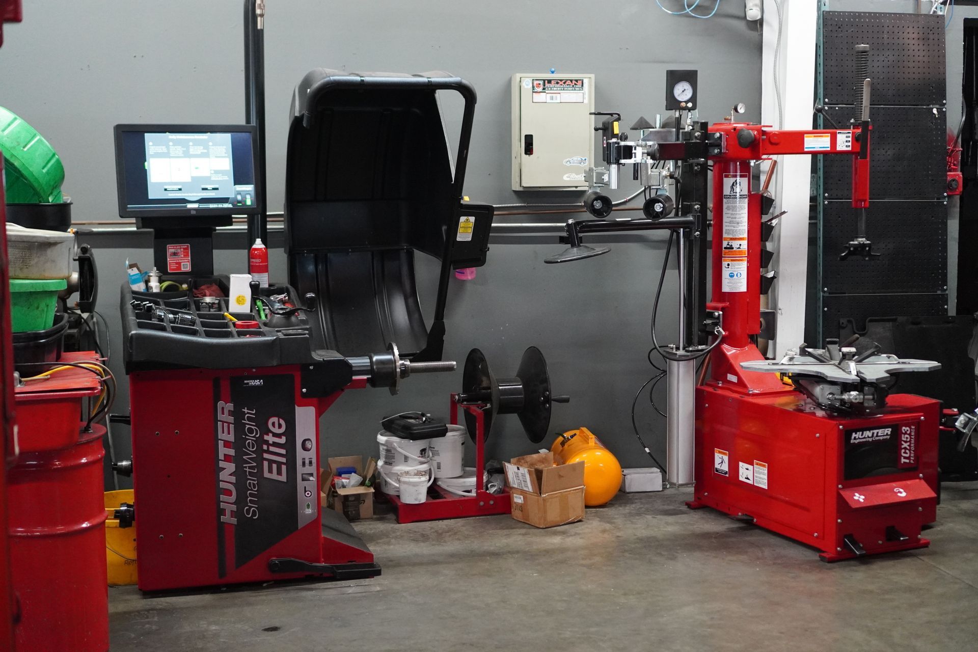 Wheel balancing and tire changing equipment in a garage. Red machines, monitor, and wheels. | Platinum Motors Martinez