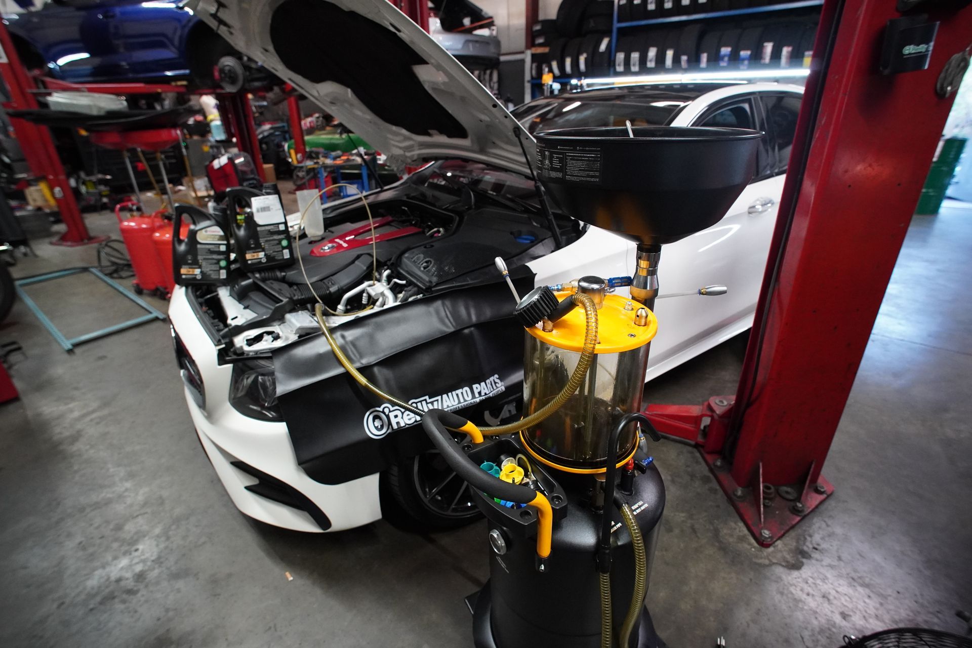 Car being serviced, oil draining into a container in an auto shop. | Platinum Motors Martinez