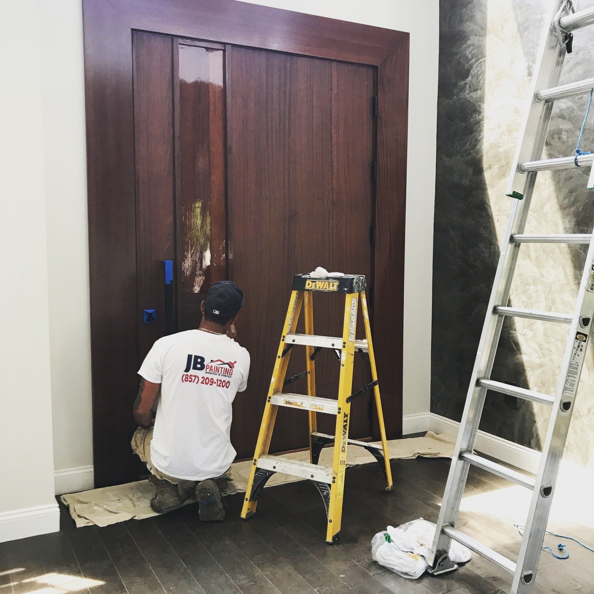 man with paintbrush painting wooden house exterior