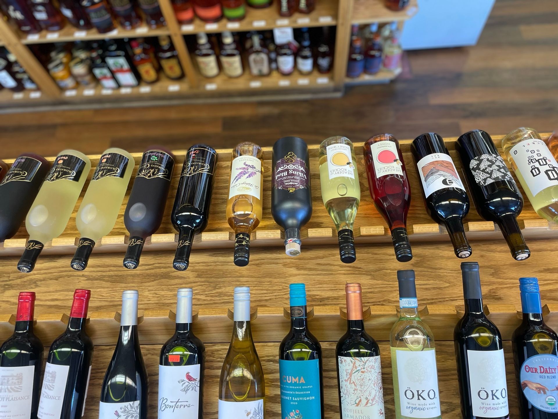 A row of wine bottles are lined up on a wooden shelf.