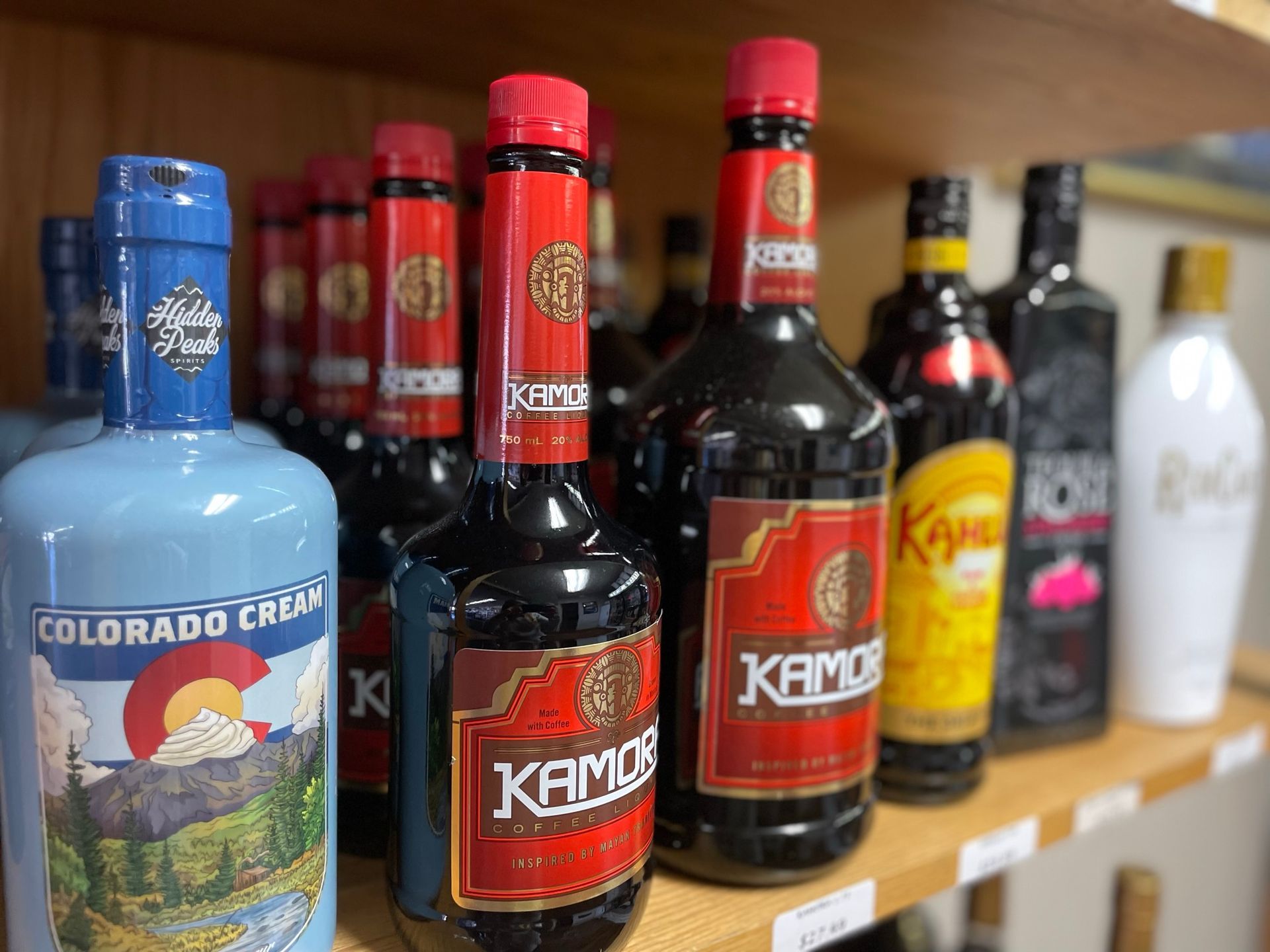 A shelf filled with bottles of liquor including a bottle of colorado cacao.