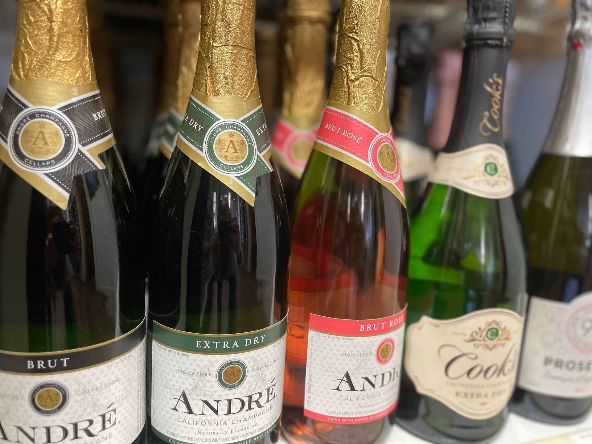 Several bottles of champagne are lined up on a shelf.