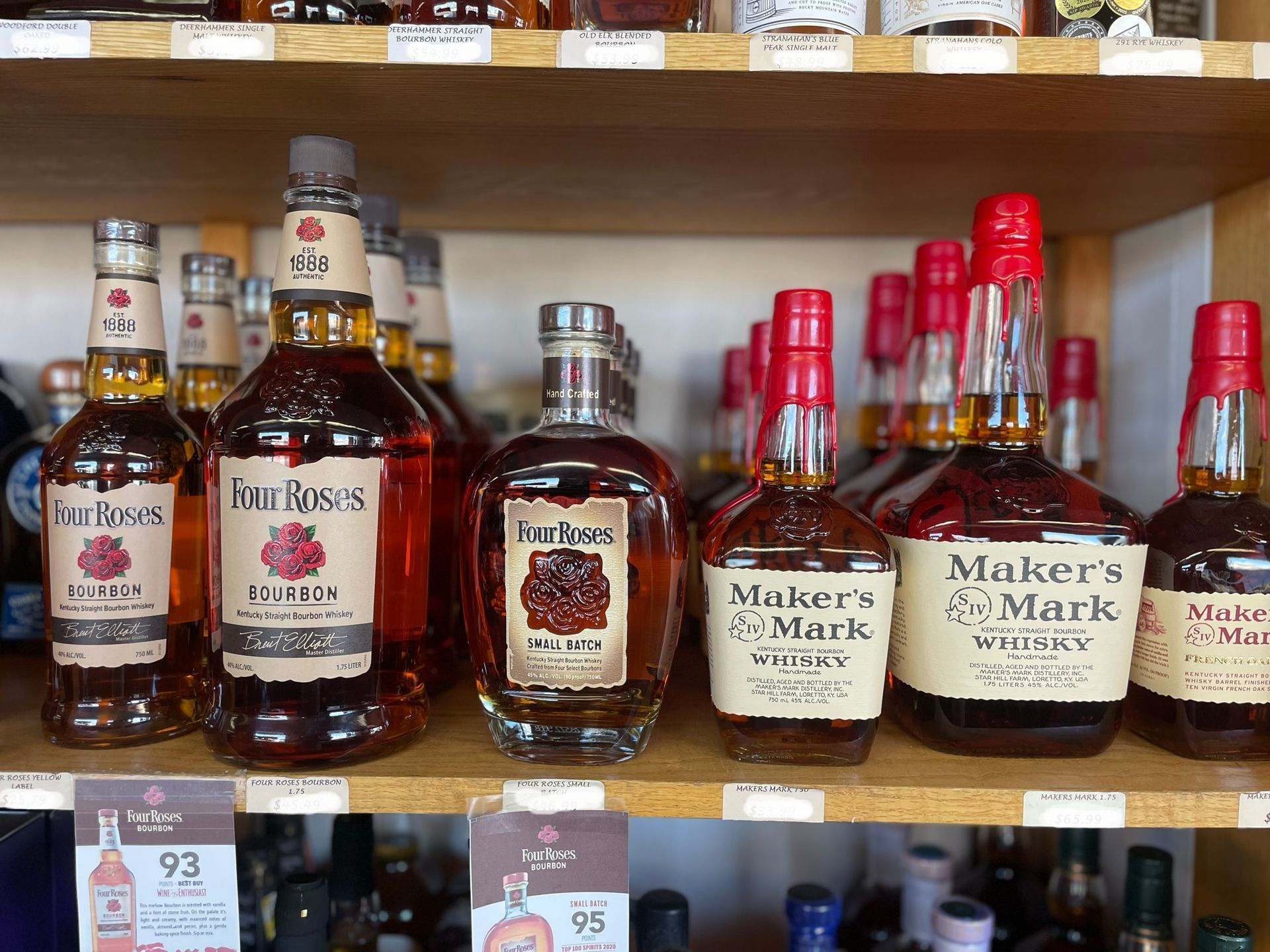 A shelf filled with bottles of makers mark whiskey