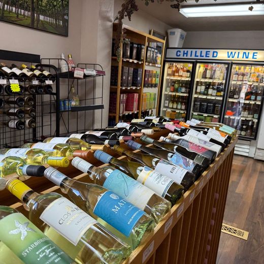 A row of wine bottles are lined up on a wooden shelf.