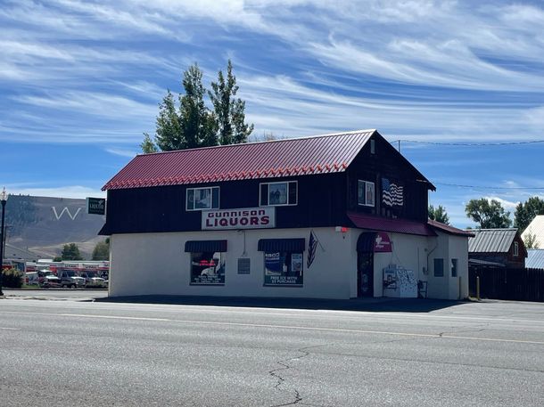 A white building with a red roof and a sign that says liquors