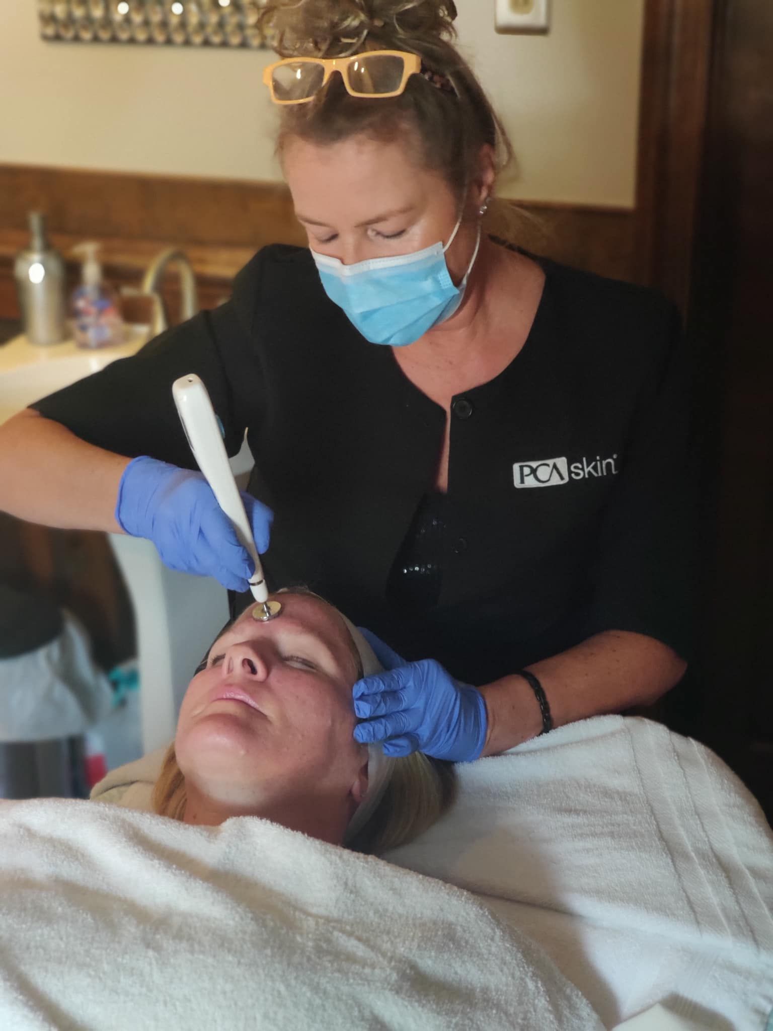 A woman wearing a mask and gloves is working on a woman 's face