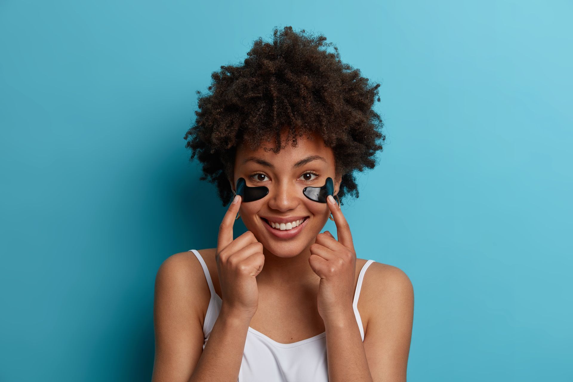 A woman is wearing black eye patches on her face.