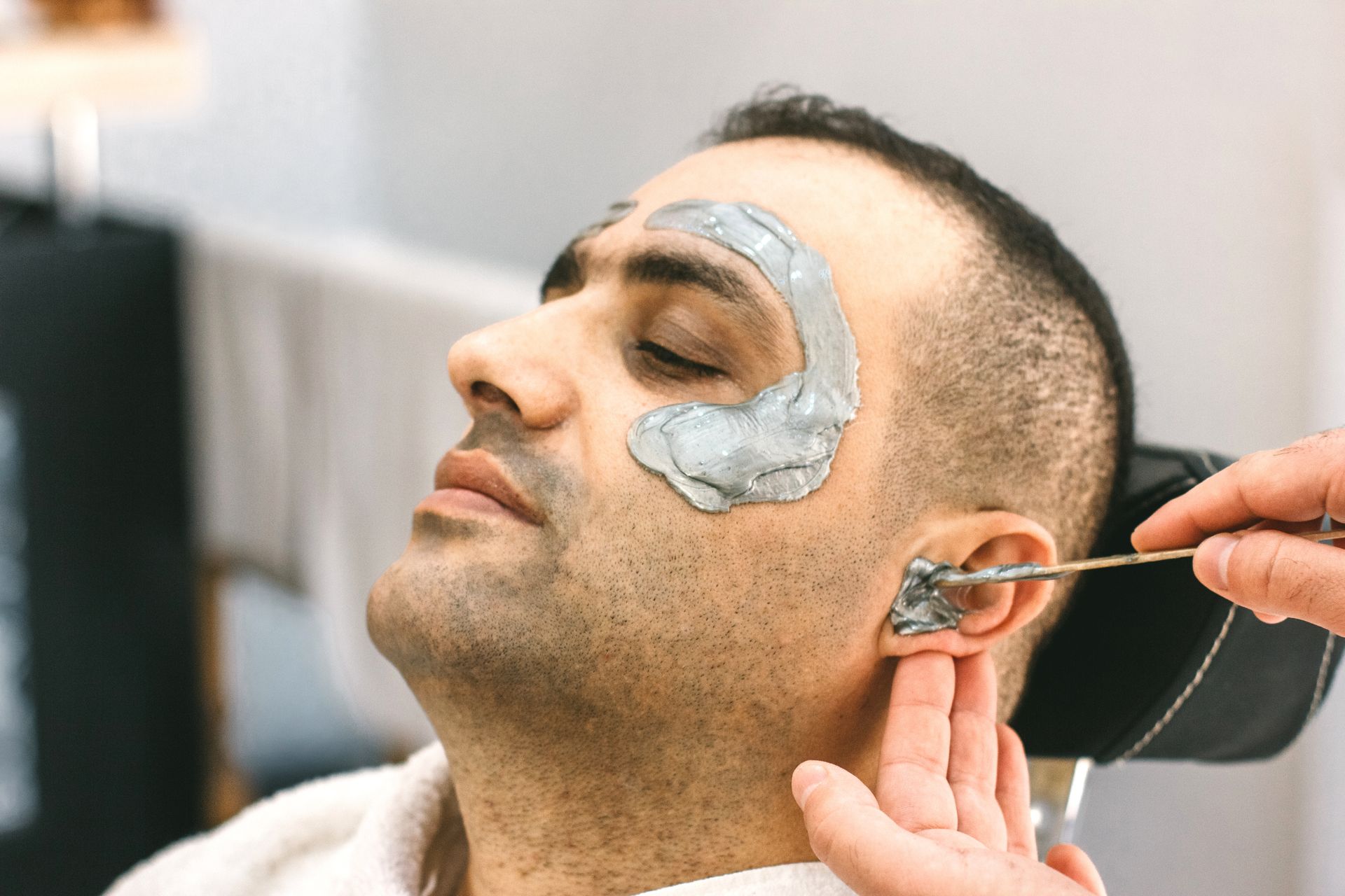 A man is getting a facial treatment at a beauty salon.