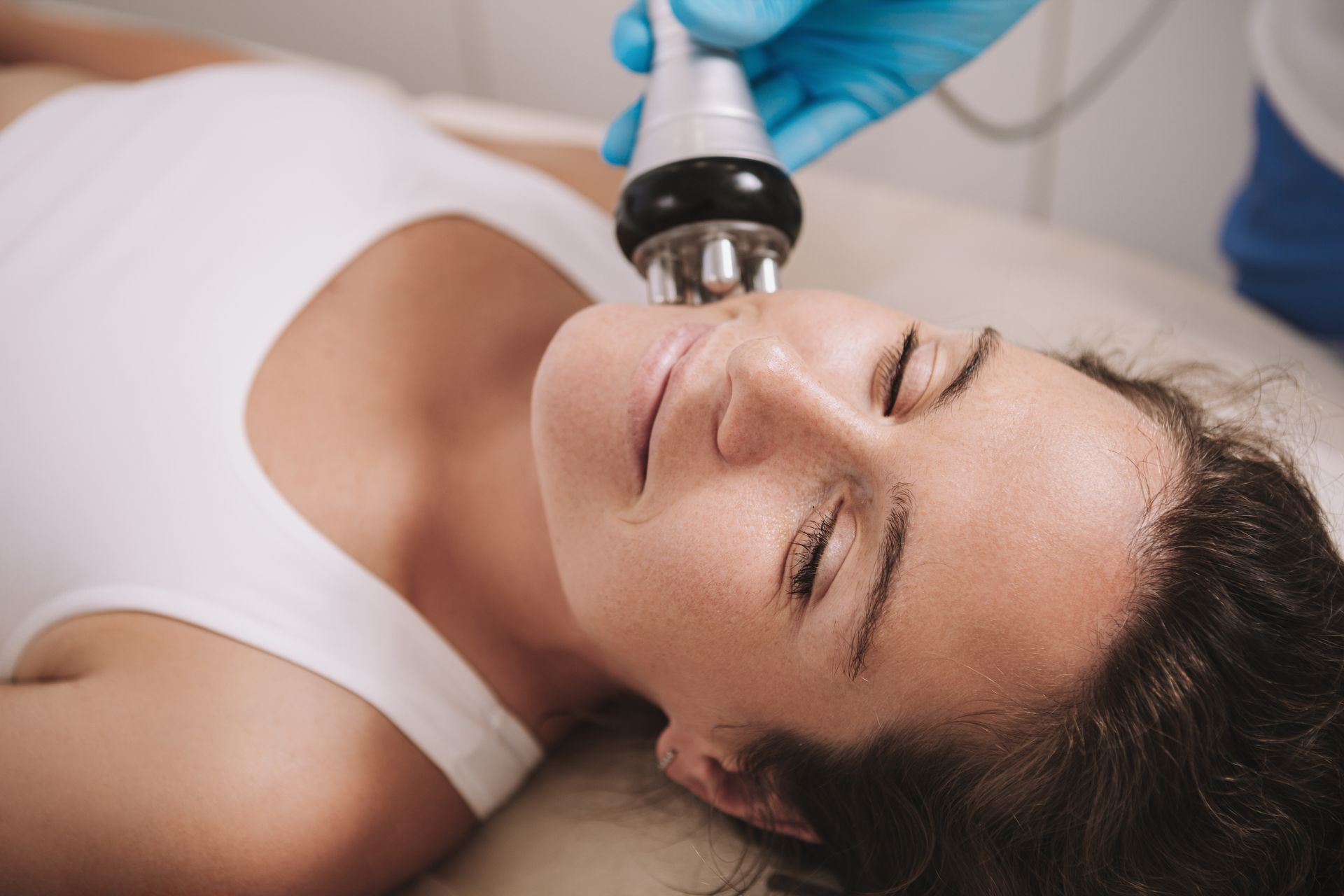 A woman is getting a facial radio frequency treatment at a beauty salon.