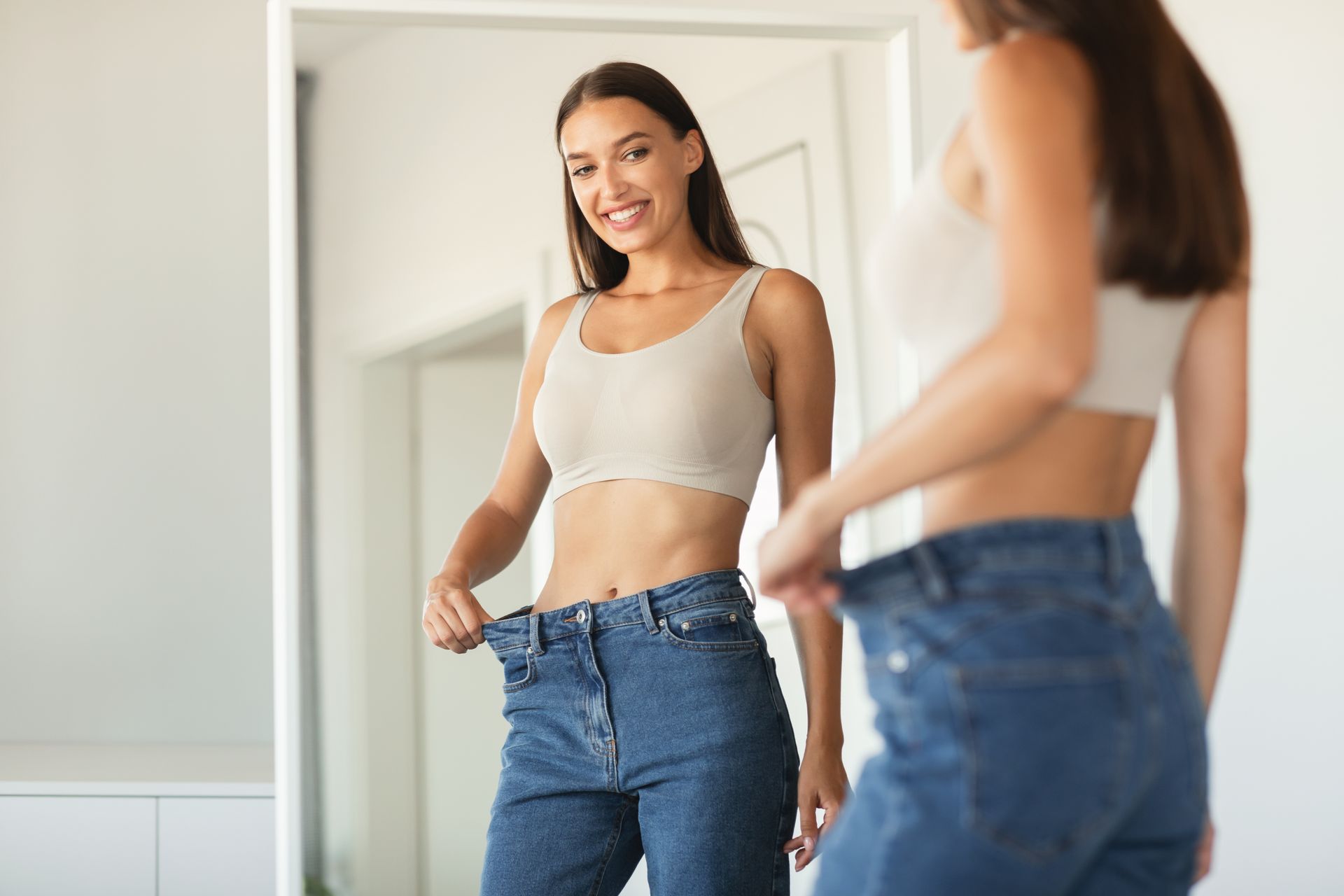 A woman is measuring her waist in front of a mirror.