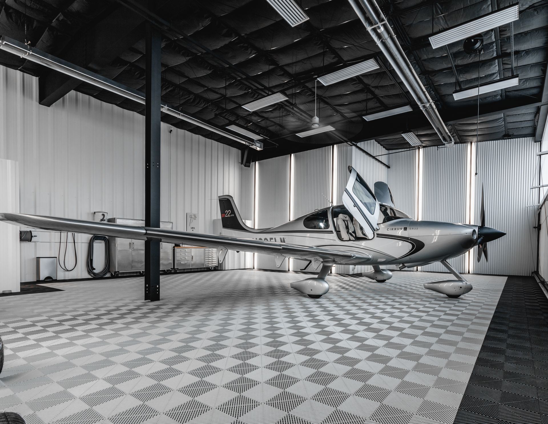 A small plane is parked in a hanger with its doors open.