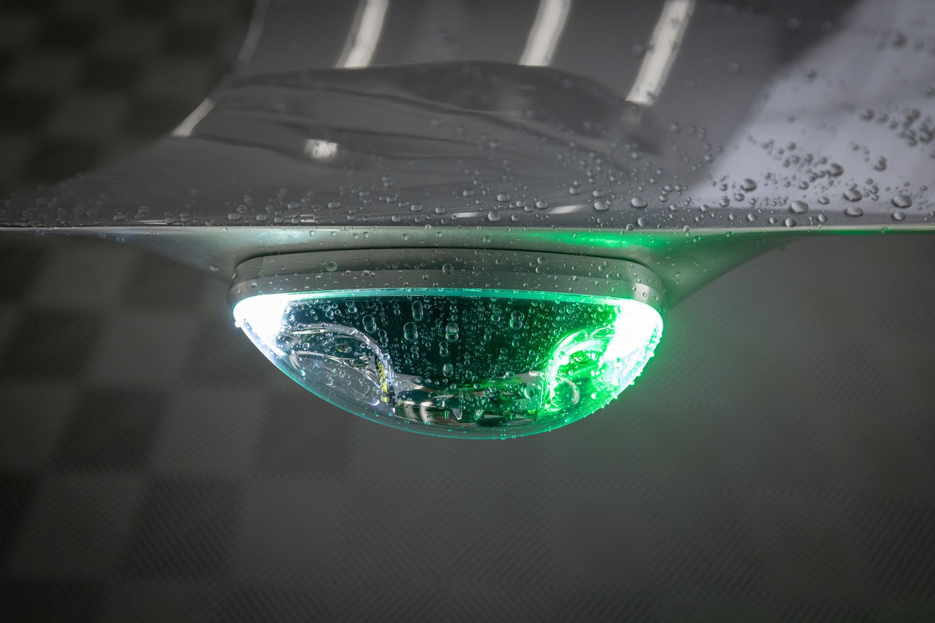 A close up of a green light on the hood of a car.