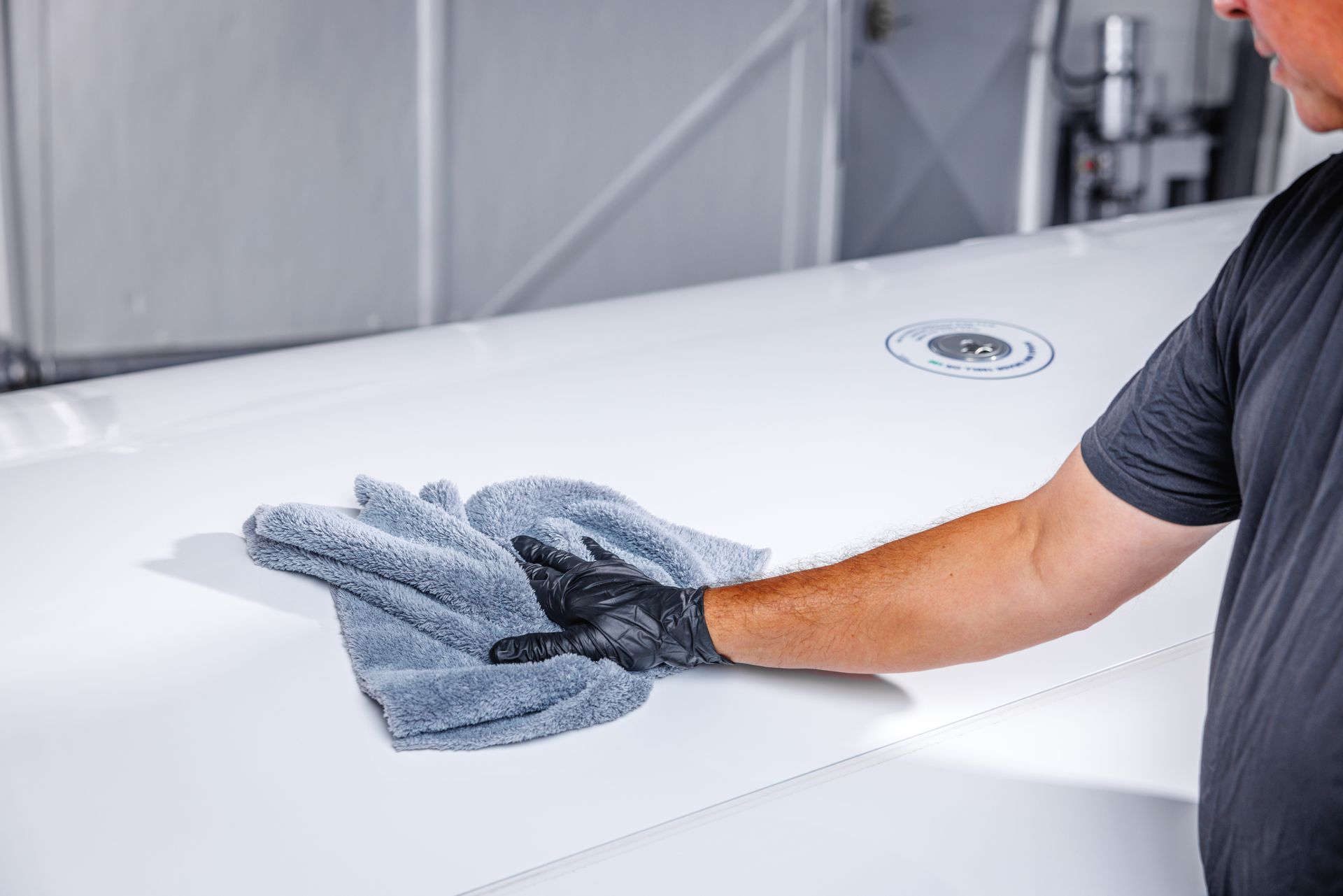 A man is cleaning a white surface with a towel.