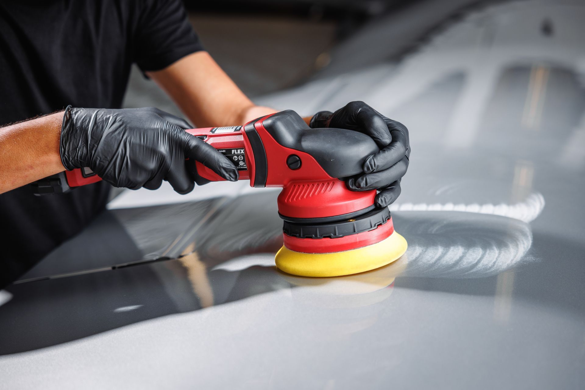 A man is polishing a car with a machine.
