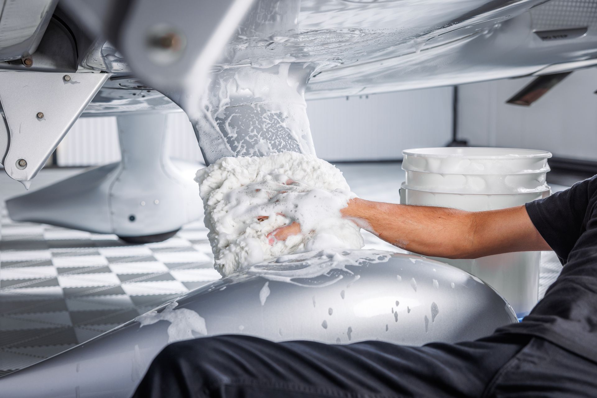 A man is washing a plane with a sponge and foam.