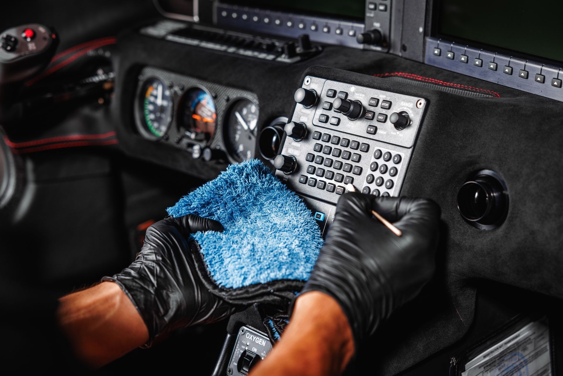 A person wearing black gloves is cleaning the dashboard of a car.