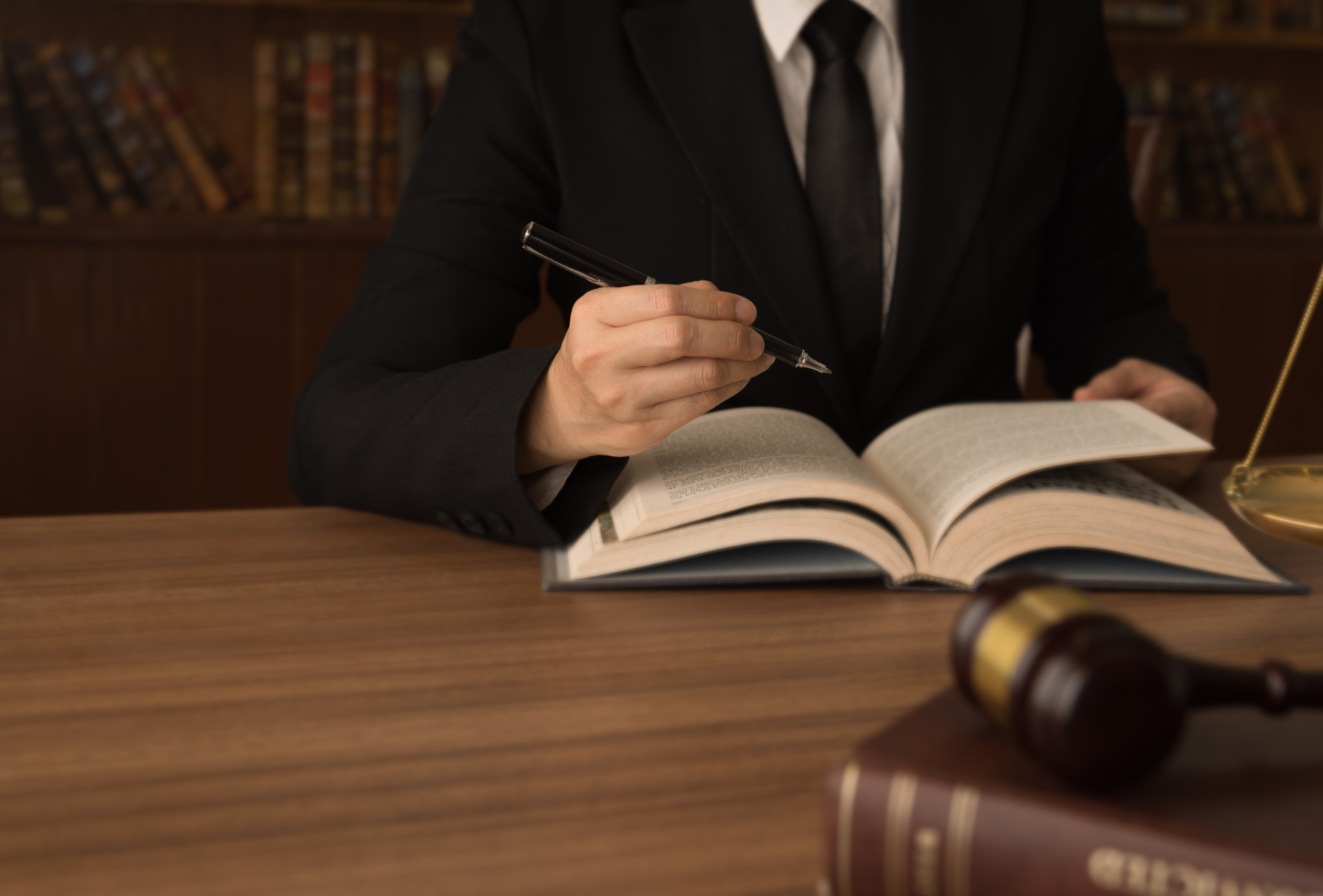A man in a suit and tie is sitting at a table reading a book.