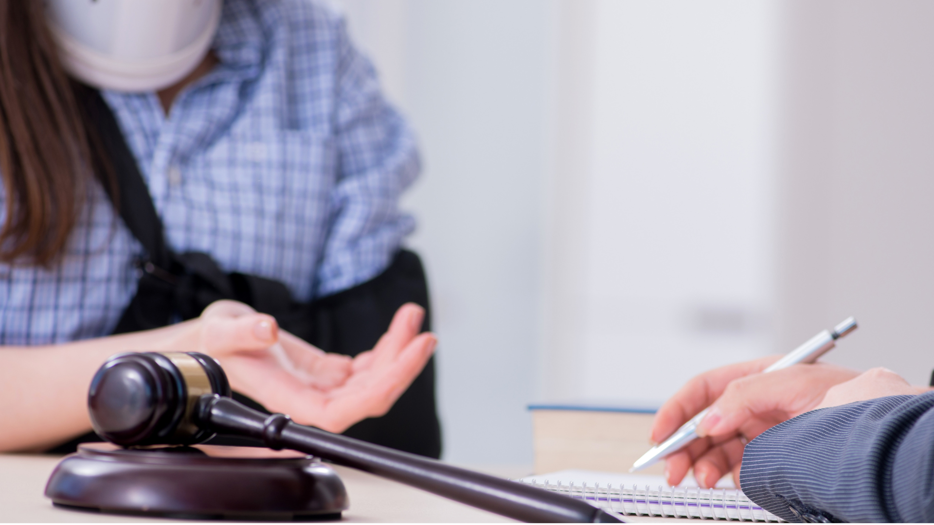 A woman in a wheelchair is sitting at a table with a judge 's gavel.