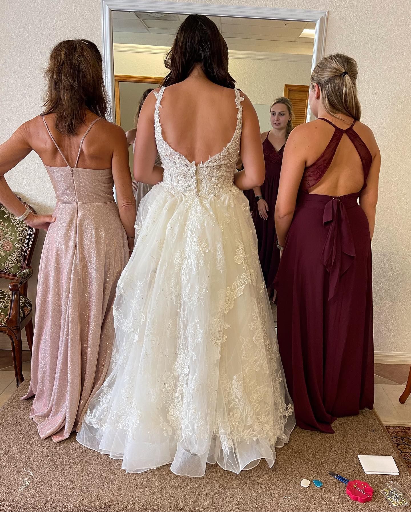 A bride and her bridesmaids are standing in front of a mirror.