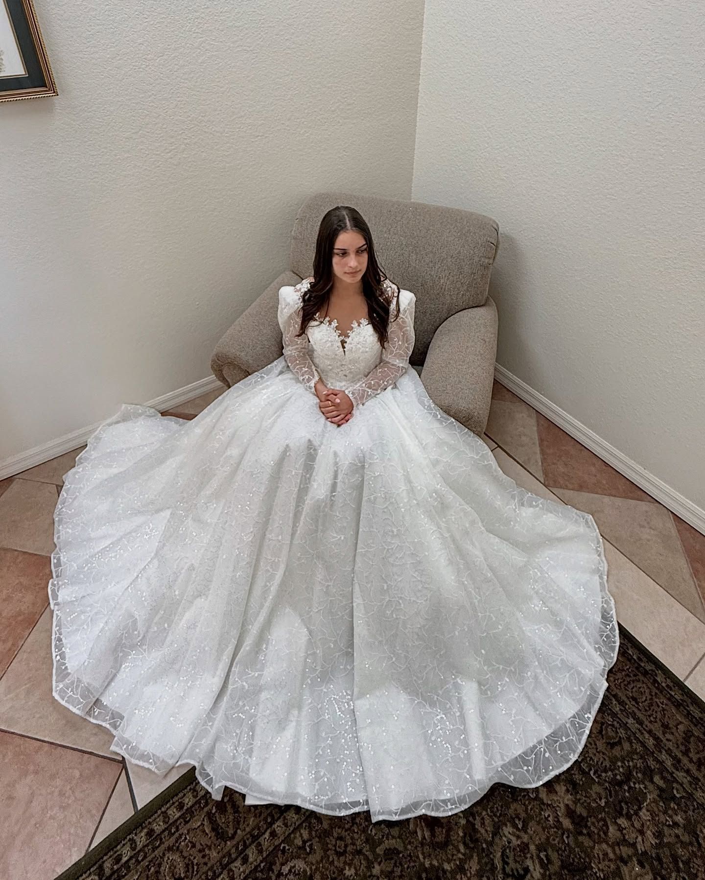 A woman in a white wedding dress is sitting in a chair.
