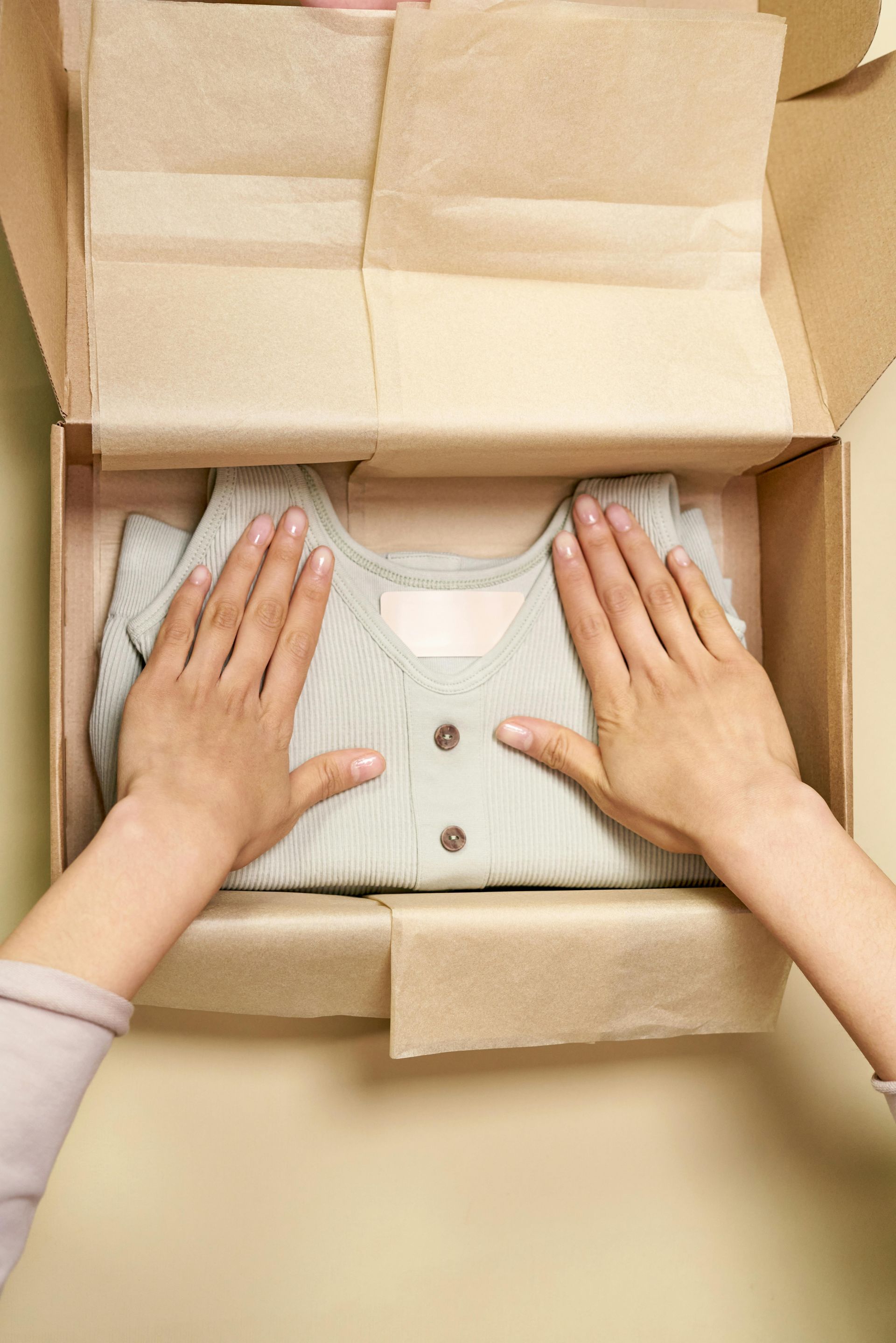 A person is putting a sweater in a cardboard box.