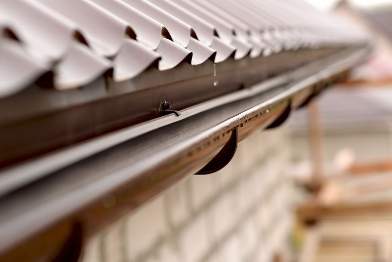 Close-up of a metal gutter with leaf guards along a roofline