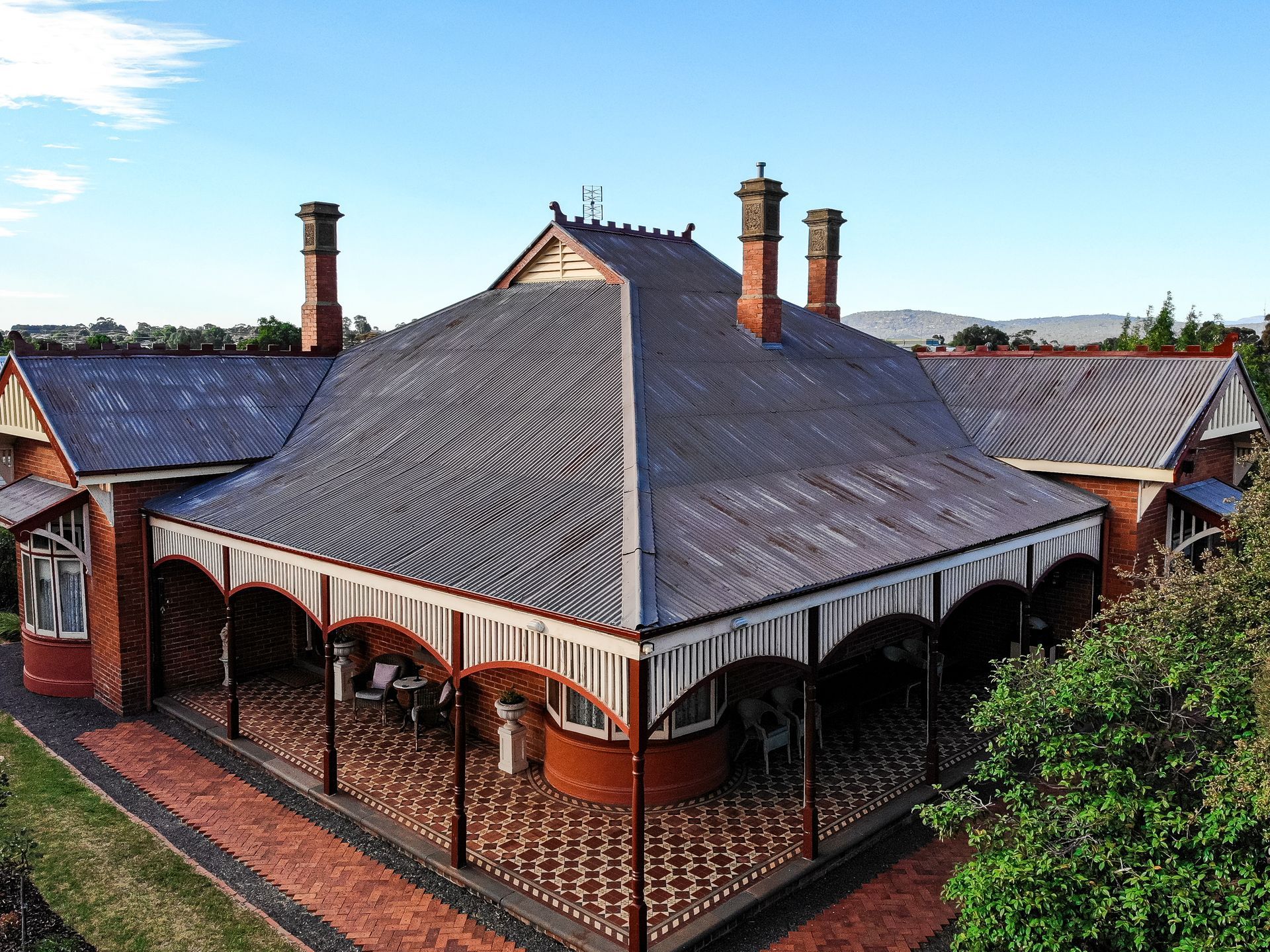 Before, worn corrugated roof with failing flashings around multiple chimneys and a wraparound verandah, Creswick VIC.