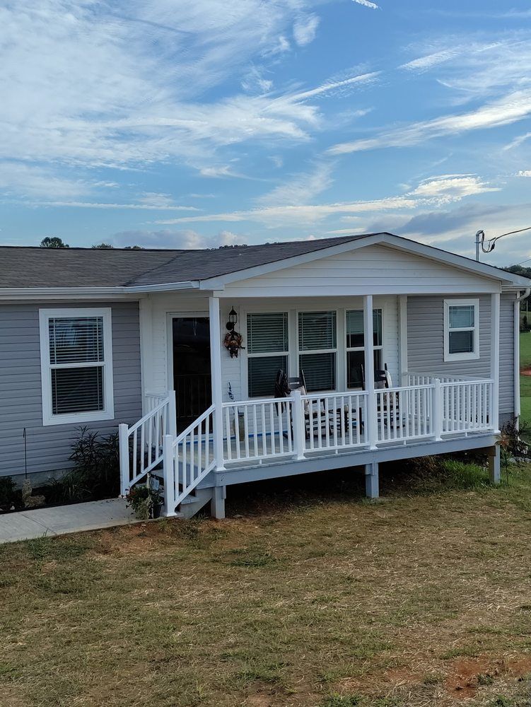 Light blue house with white porch and railing, under a cloudy blue sky.