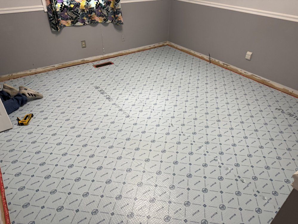 Room with light blue flooring being installed, walls are gray with wood trim.