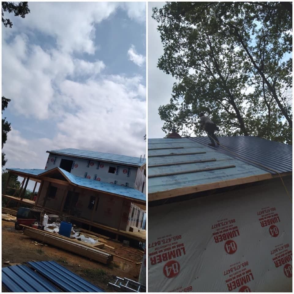 A house under construction with a blue roof, and a worker installing roofing materials under a cloudy sky.