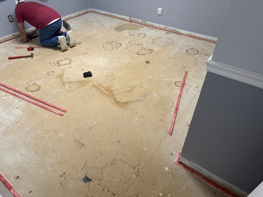 Person kneeling, working on a concrete floor with red strips around the edges.