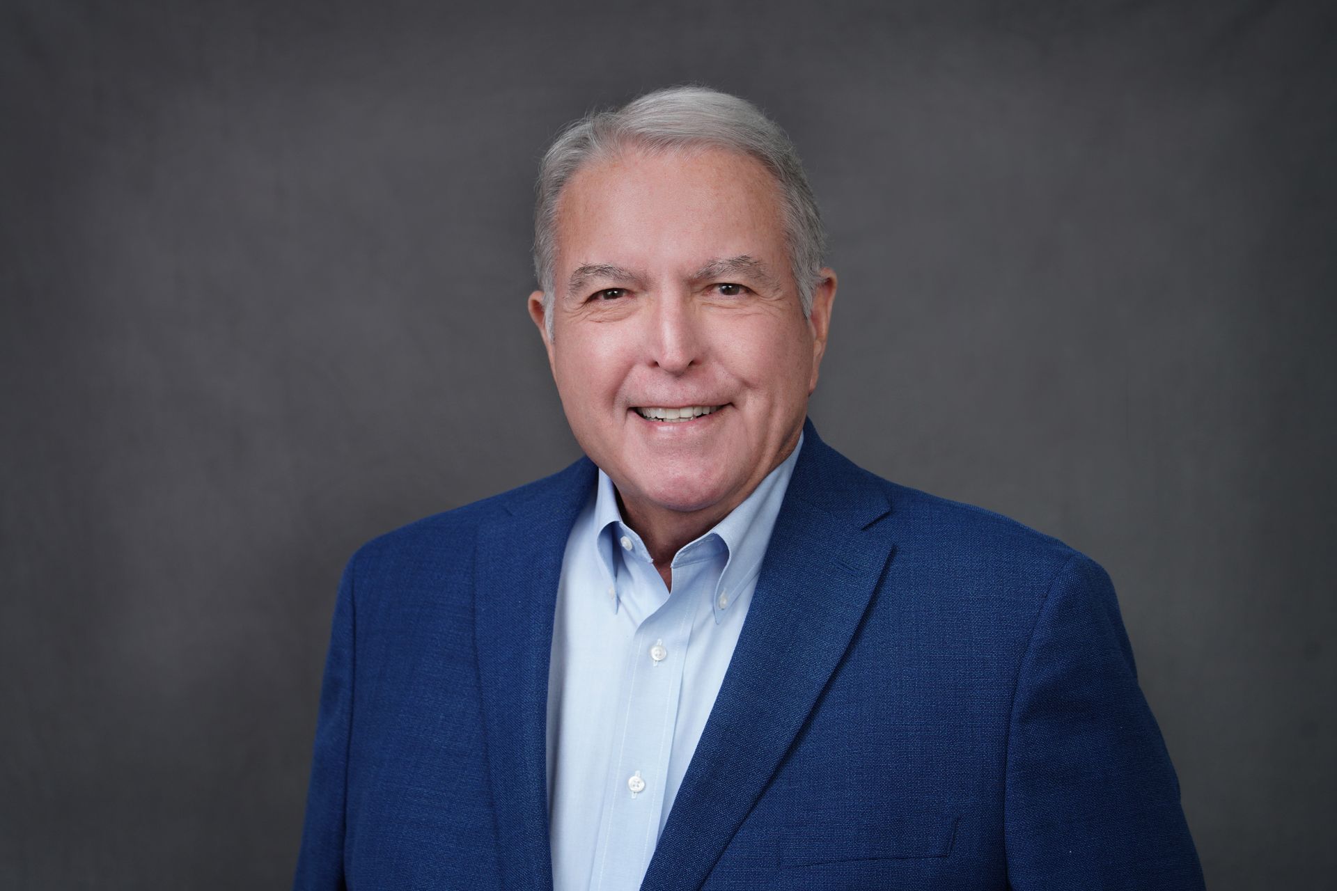 A man in a blue suit and white shirt is smiling for the camera.